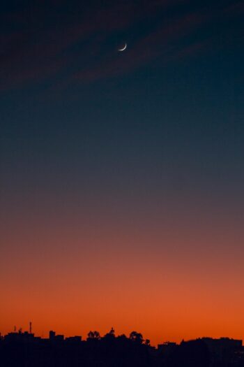 Crescent moon and fiery orange sunset horizon